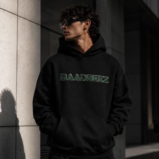 Person wearing a black hoodie with 'BAADBEEZ' logo against a dark background